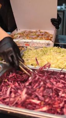 Şef şu malzemeleri kullanarak shawarma hazırlıyor: lavaş, et, sos, sebze, salatalık, soğan, lahana, baharatlı biber, patates, yeşillik, havuç