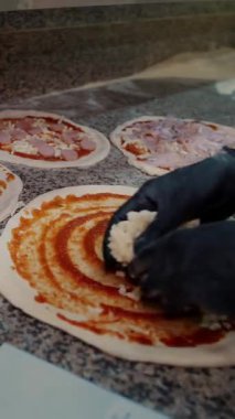 Pizza restoranın mutfağında hazırlanıyor. Şef İtalyan pizzasına peynir serper. Yakın plan yiyecek.