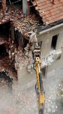 Kentsel yenilenme için harap olmuş bir binayı yıkan bir Kazıcı 'nın hava görüntüsü