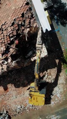 Bir yıkım sahnesinin hava perspektifinde, şehir merkezindeki yıkım ve yeniden yapılanma karışımını gösteren bir kazı makinesinin şehir alanındaki enkazı temizlediği yer.