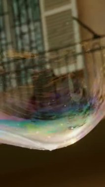 Büyük sabun köpükleri. Yakın plan. Büyük, gökkuşağı renkli, yuvarlak şekilli sabun köpükleri havada yavaşça uçar ve patlar, beyaz bir sise dönüşür..