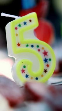 Doğum günün kutlu olsun. Kek. Yakın plan. Beş numara şeklinde bir mum. kremalı doğum günü pastası, renkli mumlar ve meyvelerle süslenmiş. Çocukların doğum günü partisi. Mutlu Aile Anları ve Anıları