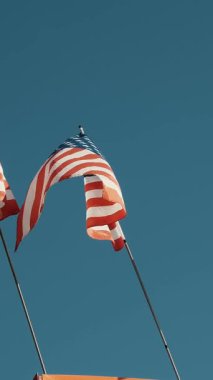 Mavi arka planda dalgalanan Amerikan Bayrakları. Amerikan Bayrağı. Mavi gökyüzünün önünde Amerika Birleşik Devletleri 'nin ünlü bayrağını sallayarak.