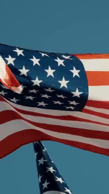 Mavi arka planda dalgalanan Amerikan Bayrakları. Amerikan Bayrağı. Mavi gökyüzünün önünde Amerika Birleşik Devletleri 'nin ünlü bayrağını sallayarak.