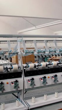 İplik üretimi. İplik yapma süreci. Dönen yapım. Tekstil fabrikası ekipmanı. Tekstil fabrikası. Fabrika makineleri makaraları ya da pamuklu ya da yün ipliklerle bobinleri geri sarıyor.