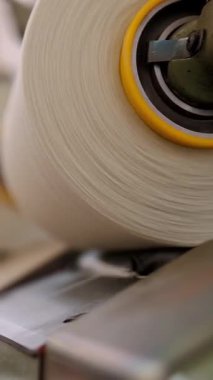 İplik ipliklerinin yakın çekim makaraları. Tekstil fabrikası ekipmanı. Tekstil fabrikası. Dönen yapım. İplik yapma süreci. İplik üretimi. Fabrika makineleri makaraları ya da pamuklu bobinleri geri sarıyor