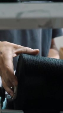 Bir işçi iplik makaraları taşır. Tekstil fabrikası ekipmanı. Tekstil fabrikası. Dönen yapım. İplik yapma süreci. Fabrika makineleri makaraları ya da pamuklu ya da yün ipliklerle bobinleri geri sarıyor.