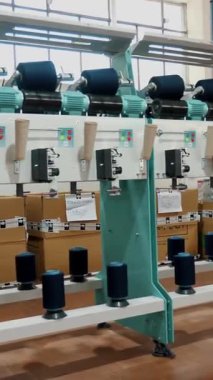 Tekstil fabrikası. İplik yapma süreci. İplik üretimi. Dönen yapım. Tekstil fabrikası ekipmanı. Fabrika makineleri makaraları ya da pamuklu ya da yün ipliklerle bobinleri geri sarıyor.