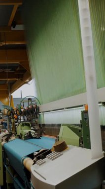 Dokuma atölyesi. Tekstil fabrikası ekipmanı. Otomatik dokuma tezgahları çalışıyor, kumaş iplikleri üretiyorlar. Tekstil endüstrisi. kumaş üretimi.