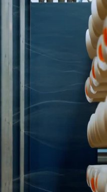 İplik makaraları. Yakın plan. Bir sürü iplik makarası olan raflar. Boyama için iplikleri hazırlama süreci, istenen rengin kumaşlarının üretimi için. otomatik çalışma süreci.