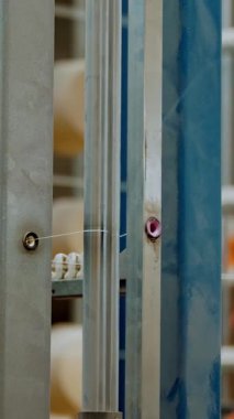 İplik makaraları. Yakın plan. Bir sürü iplik makarası olan raflar. Boyama için iplikleri hazırlama süreci, istenen rengin kumaşlarının üretimi için. otomatik çalışma süreci.