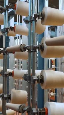 İplik makaraları. Tekstil endüstrisi. Dokuma fabrikası. Bir sürü iplik makarası olan raflar. Daha fazla kumaş üretimi için ipliklerin boyanıp kurutulması. Otomatik çalışma süreci. tekstil üretimi.