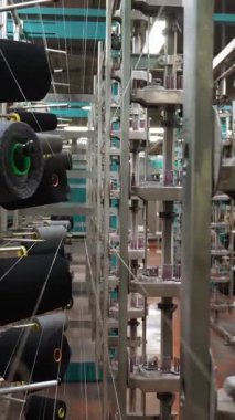 İplik makaraları. Tekstil endüstrisi. Dokuma fabrikası. Bir sürü iplik makarası olan raflar. Daha fazla kumaş üretimi için ipliklerin boyanıp kurutulması. Otomatik çalışma süreci. tekstil üretimi.