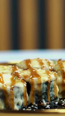 Suşi. Japon yemeği. Yakın plan. Siyah tabakta servis edilen taze pişmiş suşi ruloları dönüyor. Yemek pişirmek. Mutfak. Asya yemekleri
