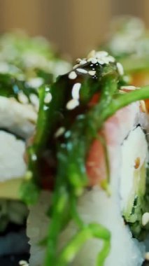 Suşi. Japon yemeği. Yakın plan. Siyah tabakta servis edilen taze pişmiş suşi ruloları dönüyor. Yemek pişirmek. Mutfak. Asya yemekleri