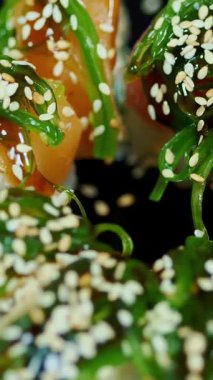 Suşi. Japon yemeği. Yakın plan. Siyah tabakta servis edilen taze pişmiş suşi ruloları dönüyor. Yemek pişirmek. Mutfak. Asya yemekleri