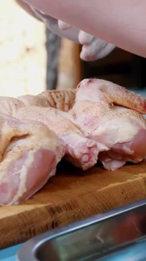 Korkak. Yemek pişirmek. Yakın plan. Şef taze çiğ tavuğu baharat ve tuz ile kesme tahtasına sürterek serpiyor. Şef pişirmek için tavuk pişirir.