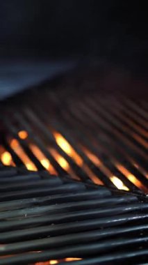 Izgara yap. Arka planda boş siyah ızgara ızgarası. Restoran mutfağında büyük ızgara çeviriyor. Izgaranın altından sıcak, buharlı, parlayan ateş görülebilir. Barbekü.