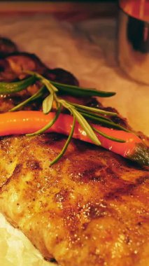 Izgara et servisi. Yemek pişirmek. Yakın plan. Şef sulu ızgara domuz pirzolası, sos, biberiye ve acı biberle süslüyor. Şeften bir tabak..