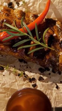 Izgara et servisi. Yemek pişirmek. Yakın plan. Güzel, sulu bir et parçası, kokulu otlar, sos ve baharatlar, dönen tabakta. Restoran. Sanat aşçılığı.