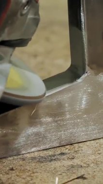 Grinding of metal products. close-up. A man in gloves grinds metal products with a grinder machine, angle grinder in workshop, at the enterprise. Sparks fly