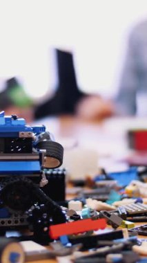 Masanın üzerinde çocuk tasarımcısının, küplerin, kabloların, tahtaların, tekerlerin, renkli küçük robotların ve makinelerin bir sürü detayı var. Çocuklar robotiğe, programlamaya, modellemeye düşkündür.,