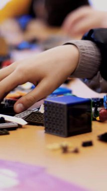 Masanın üzerinde çocuk tasarımcısının, küplerin, kabloların, tahtaların, tekerlerin, renkli küçük robotların ve makinelerin bir sürü detayı var. Çocuklar robotiğe, programlamaya, modellemeye düşkündür.,