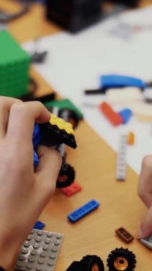 Yakın plan, çocukların elleri bir tasarımcıdan monte edilmiş çok renkli küçük bir robot, bir makine tutuyor. Çocuklar robotiğe, programlamaya, modellemeye düşkündür.,