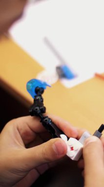 Yakın plan, çocukların elleri bir tasarımcıdan monte edilmiş çok renkli küçük bir robot, bir makine tutuyor. Çocuklar robotiğe, programlamaya, modellemeye düşkündür.,