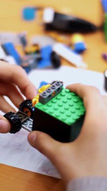 Yakın plan, çocukların elleri bir tasarımcıdan monte edilmiş çok renkli küçük bir robot, bir makine tutuyor. Çocuklar robotiğe, programlamaya, modellemeye düşkündür.,