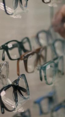 Yakın plan, optik mağazada vitrin, optik, gözlükçü, perakende, gözlük dükkanı, bir sürü gözlük, çerçeve, adamın eli moda düzeltici gözlük, gözlük seçiyor. .