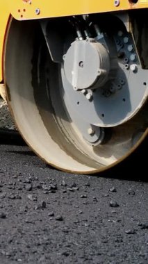 yakın çekim, yol yapımı silindir kompaktör makine ve asfalt son işlemci ile çalışır. Taze asfalt kaplama üzerine çakıl yol yapımı sırasında temel döşeme yol silindiri