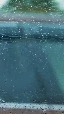 Araba sürerken arabanın yan camına bir damla su damlatıyor. Bu fotoğrafçı adam yağmur yağarken arabasını kullanıyor.