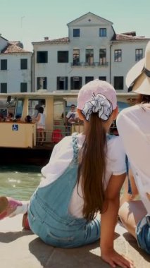 Venice, İtalya - 7 Temmuz 2018: turist, şapkalı kadın ve Venedik, büyük kanal manzarasına hayran bir kız. vapareto yüzen su, küçük tekneler, gondol yelken, sıcak yaz gününde,