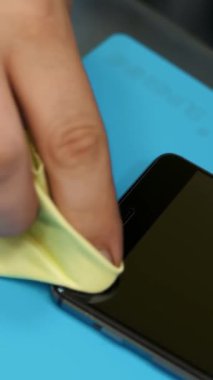 holding ve bir cep telefonu ekran temizleme erkek ellerini koymak, geçerli bir smartphone, bakım destek ve tamir servisi korumak için koruyucu bir temperli cam