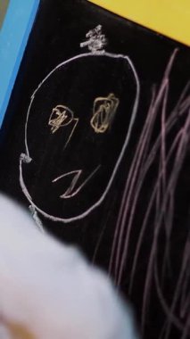 Yakın plan, çocukların elinde tebeşir, karatahtaya resim çizer..