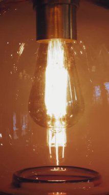 Lambayı açıp kapamak, avize. Yakın plan. Edison filamanlı ampul. Parlayan lamba. Edison filamanlı klasik tip lamba kapanıyor ve açılıyor..