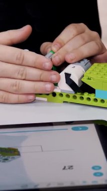 Öğrenciler, tabletteki çizimlere göre tasarımcıyı kullanarak bir cihaz oluşturuyorlar. Robot Bilimi Okulu, Kök Eğitimi