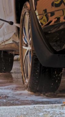 Araba yıkama, adam araba yıkama. Araba jantlarını ve tekerlekleri temizliyor temiz su ile yüksek basınçlı sprey, self servis araba yıkama, açık havada