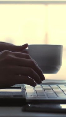 yakın çekim, erkek bir şey tipik bir dizüstü klavye üzerinde eller. aynı zamanda, bir iş kadını kahvesini beyaz bir bardaktan içer