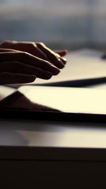 portre, karanlık eller silüeti. o bir şey tablet yazmakta olduğunu, sonraki tablo bir fincan, telefon, laptop. Bulanık pencere arka plan, bir ışık ışını tablet ekran yansıtılır