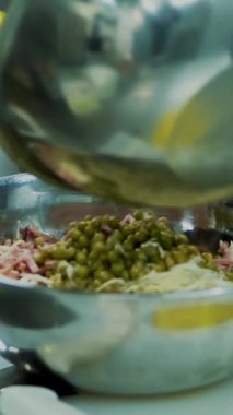 yakın çekim, metal bir kase salata kasesi mayonez sebze salatası yemek. aşçı tüm malzemeyi karışımları, birkaç kaşık mayonez ve biber koyar.