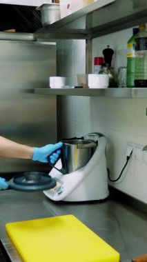 Kantinde ticari mutfak var. Aşçı özel bir ev aleti kullanıyor, endüstriyel karıştırıcı, yemek pişirmek için..