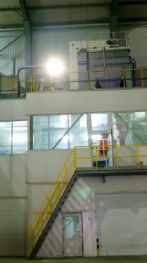 Modern bir fabrikanın içi, endüstriyel büyük hangar girişi, depo. Santral, borular, merdivenler, paneller, çeşitli teknik otomatik süreçlerin kontrol panelleri için büyük çelik yapılar.