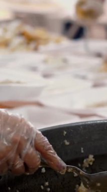 Yakın plan, kadın gönüllü lapayı büyük tavadan yemek kutusuna koyar. Yoksul ve evsizler için sıcak yemek. Bedava yemek servisi. bağış yardımı,