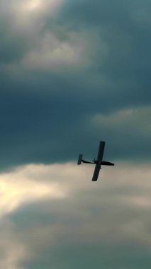 Koyu fırtına bulutlarıyla mavi gökyüzüne doğru uçan Retro uçak. Güneş ışınları bulutları delip geçiyor