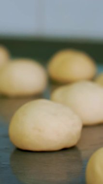 Yemek pişirmek. Fırın ürünleri. Yakın plan. Çörekler için çiğ maya hamuru bir tavada, bitkisel yağla yağlanmış olarak duruyor. Sağlıklı yemek. Güvenlik kavramı. Matarayı yeniden açıyorum. Gönüllülük ve yardım