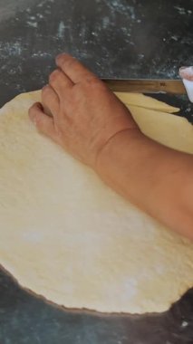 Yemek pişirmek. Fırın ürünleri. Yakın plan. Kadın elleri hamuru mutfak masasında un serpiştirerek parçalara ayırıyor. Sağlıklı yemek. Matarayı yeniden açıyorum. Gönüllülük ve yardım