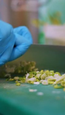 Yemek pişirmek. Yakın plan, koruyucu eldivenli şef, yemek tahtasında yeşil soğan kesiyor. Sağlıklı yemek. Güvenlik kavramı. Matarayı yeniden açıyorum. Gönüllülük ve yardım