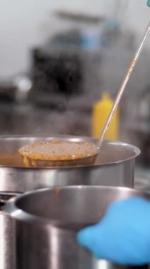 Yemek pişirmek. Yakın plan. Şef sıcak portakal çorbasını büyük bir tencereden daha küçük bir kaba döker. Sağlıklı yemek. Gönüllü olmak ve yardım. Matarayı yeniden açıyorum. güvenlik kavramı.